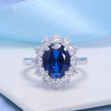 Silver ring with a blue gemstone and diamond accents on a light blue background