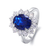 Silver ring with a blue gemstone and clear stones on a white background