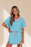 Woman wearing a blue and pink outfit with a beige background
