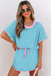 Woman wearing a light blue outfit with pink trim against a white background