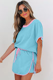 Woman wearing a light blue outfit with pink accents on a plain background