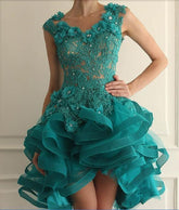 Teal lace dress with floral details and ruffled skirt against a neutral background