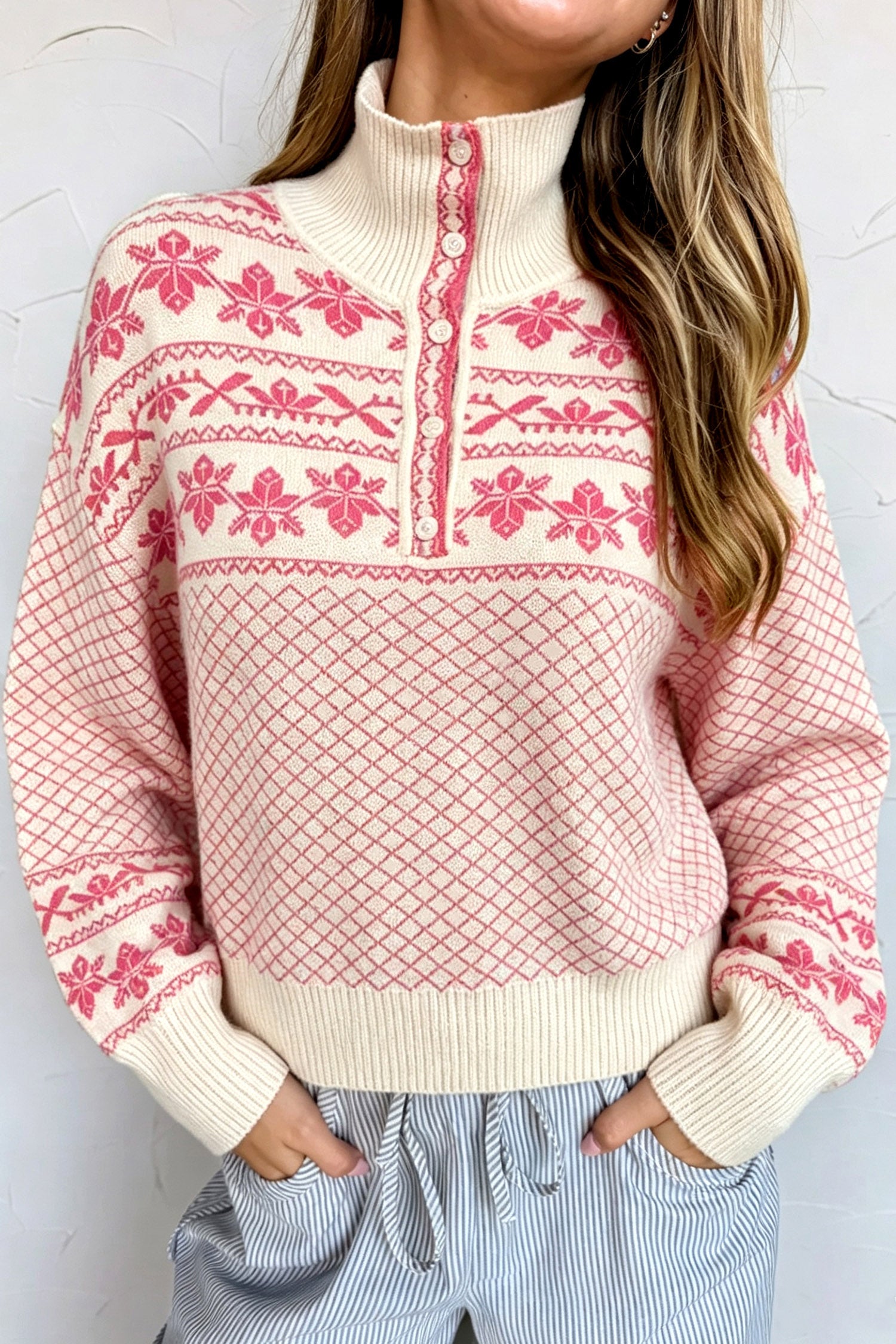 Woman in a cream and pink Fair Isle sweater with mock neck, paired with striped pants.