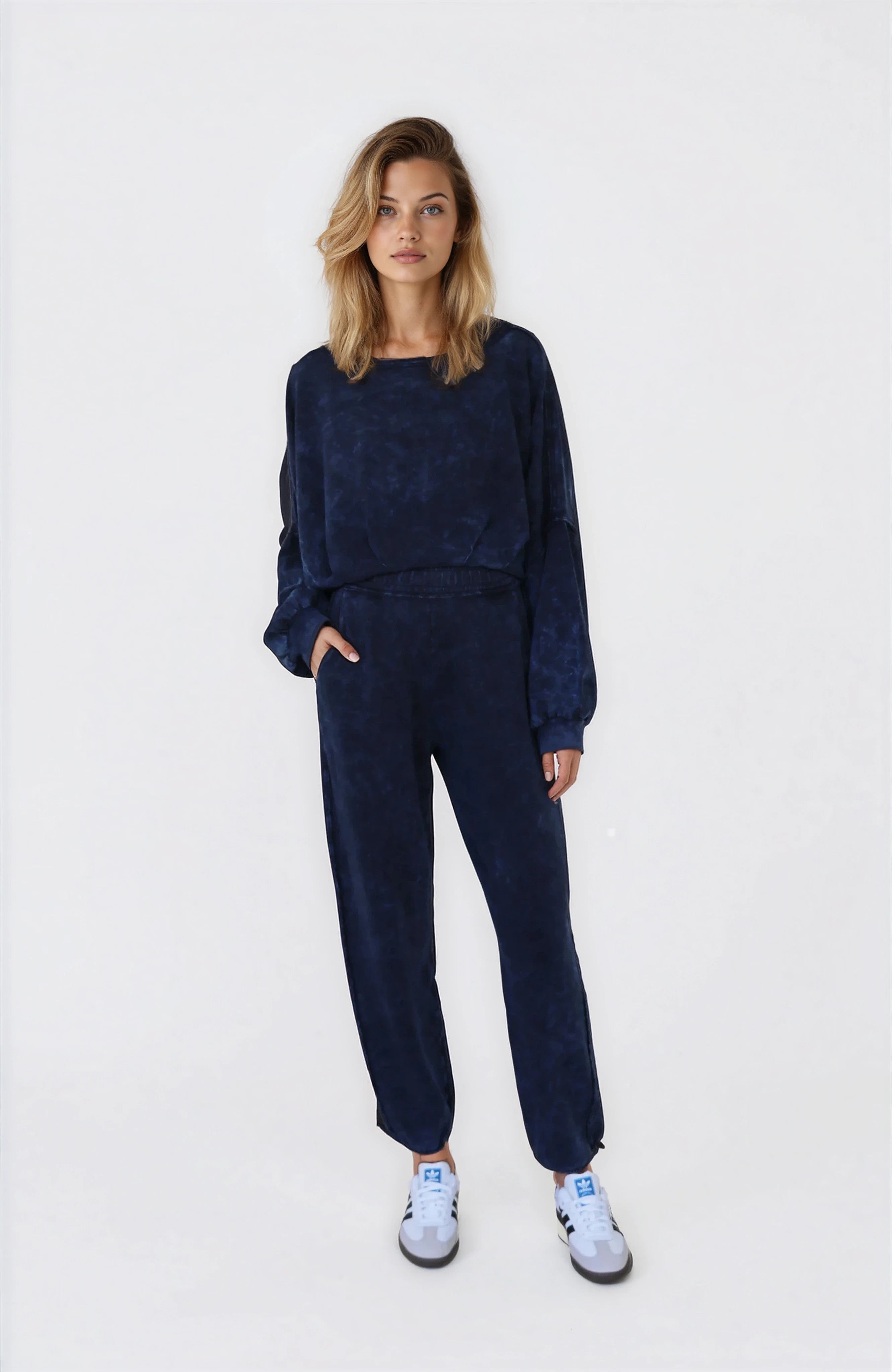 Woman wearing a navy blue outfit with white sneakers on a white background