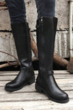 Black knee-high boots worn by a person standing on a wooden floor with a rustic background.