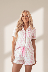 Woman wearing a pink floral pajama set against a neutral background