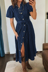 Woman wearing a blue denim dress with a slit, standing in a room.