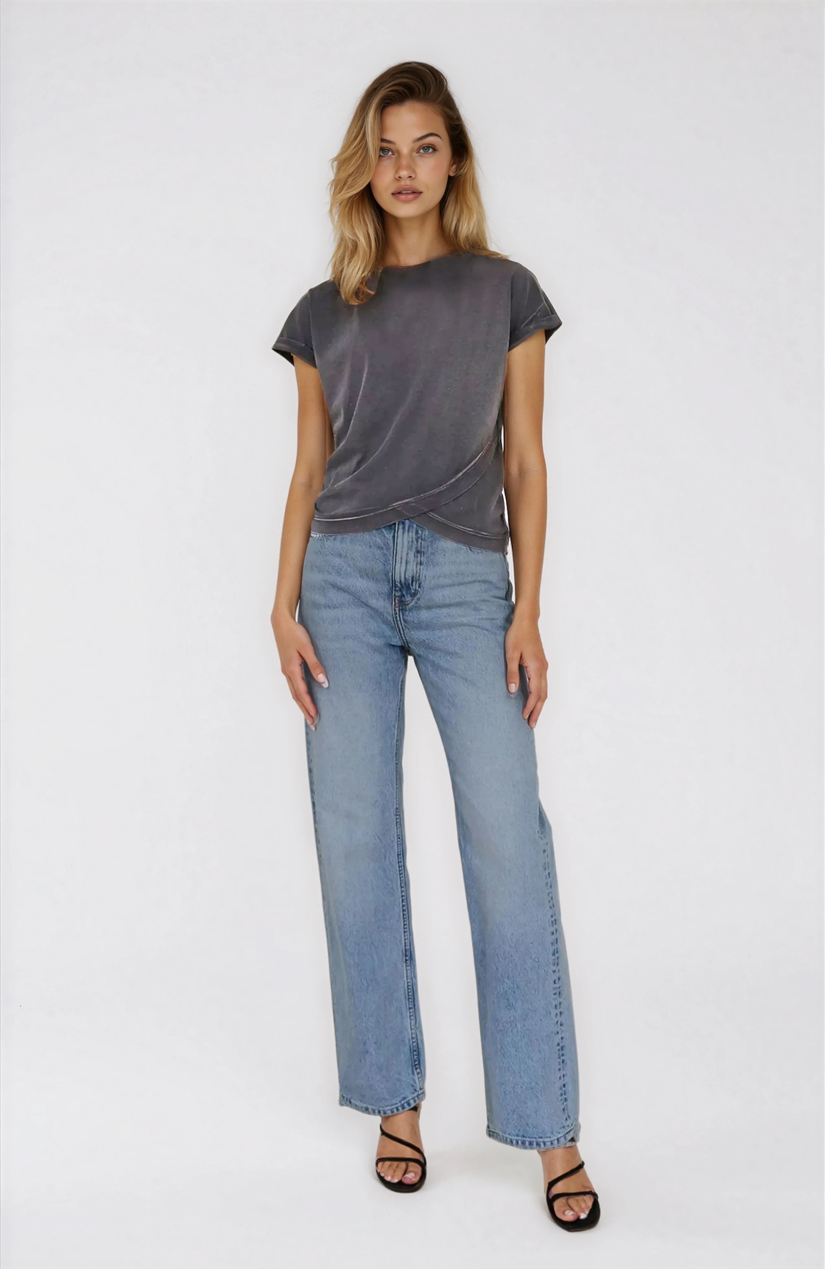Woman wearing a gray t-shirt and light blue jeans on a white background