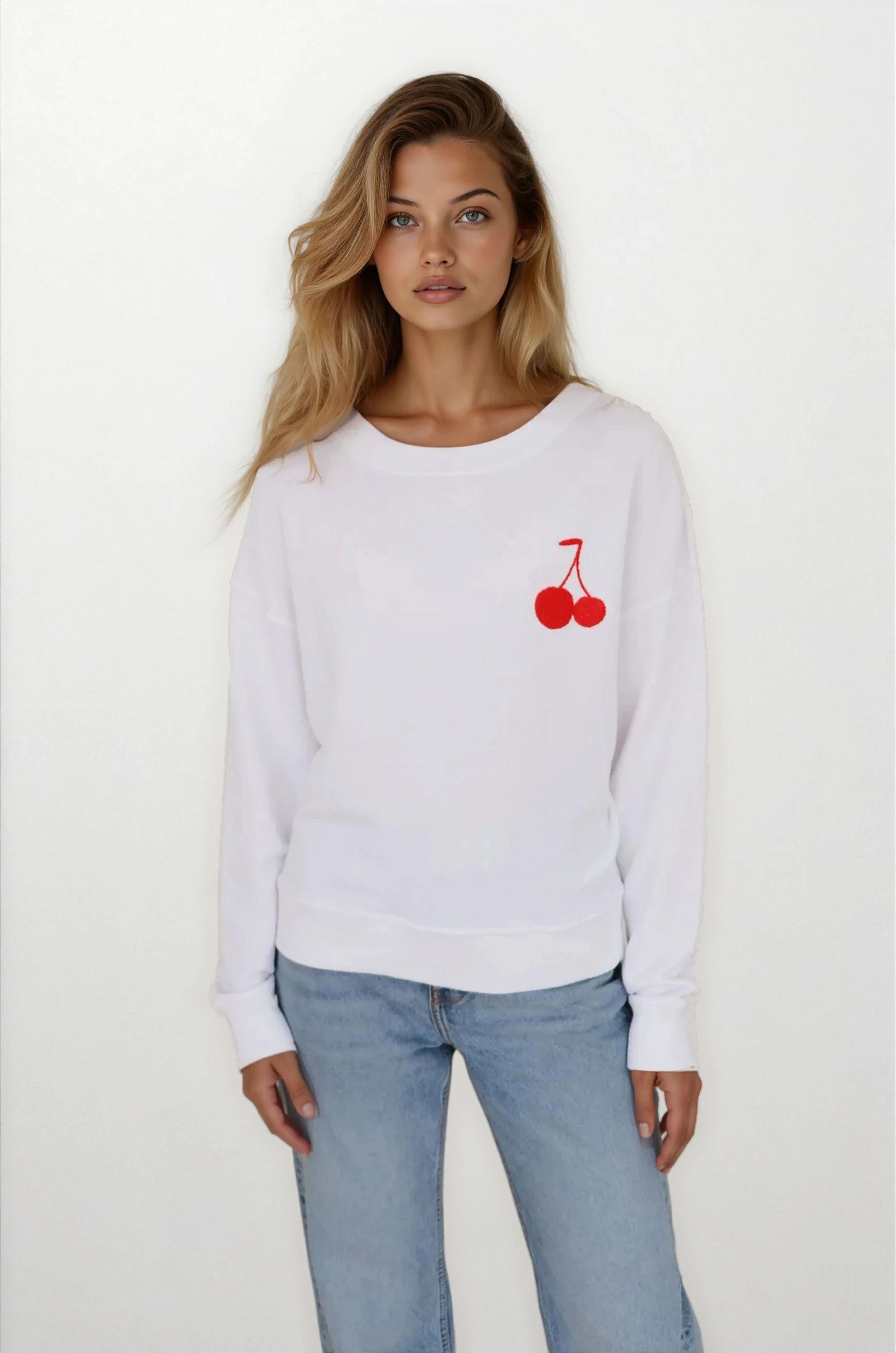Woman wearing a white sweatshirt with red cherry design on a plain background