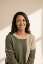 Woman wearing a green and beige sweater with a neutral background