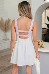 Woman wearing a white dress with a checkered back design in an indoor setting.