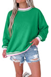 Woman in bright green sweatshirt with pink-white striped trim and distressed denim shorts.