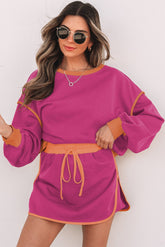Woman wearing a pink dress with orange accents against a white background