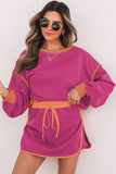 Woman wearing a pink dress with orange accents against a white background