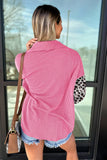 Woman in pink and white striped shirt with leopard print sleeves standing in front of glass door.