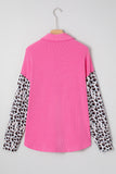 Pink long-sleeve shirt with ribbed body and leopard-print sleeves on wooden hanger against light gray.