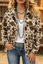 Woman wearing brown and beige cow-print jacket with turquoise necklaces and western belt by wooden fence.