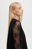 Woman wearing a black lace top against a white background