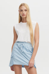 Woman wearing a white sleeveless top and light blue skirt on a white background
