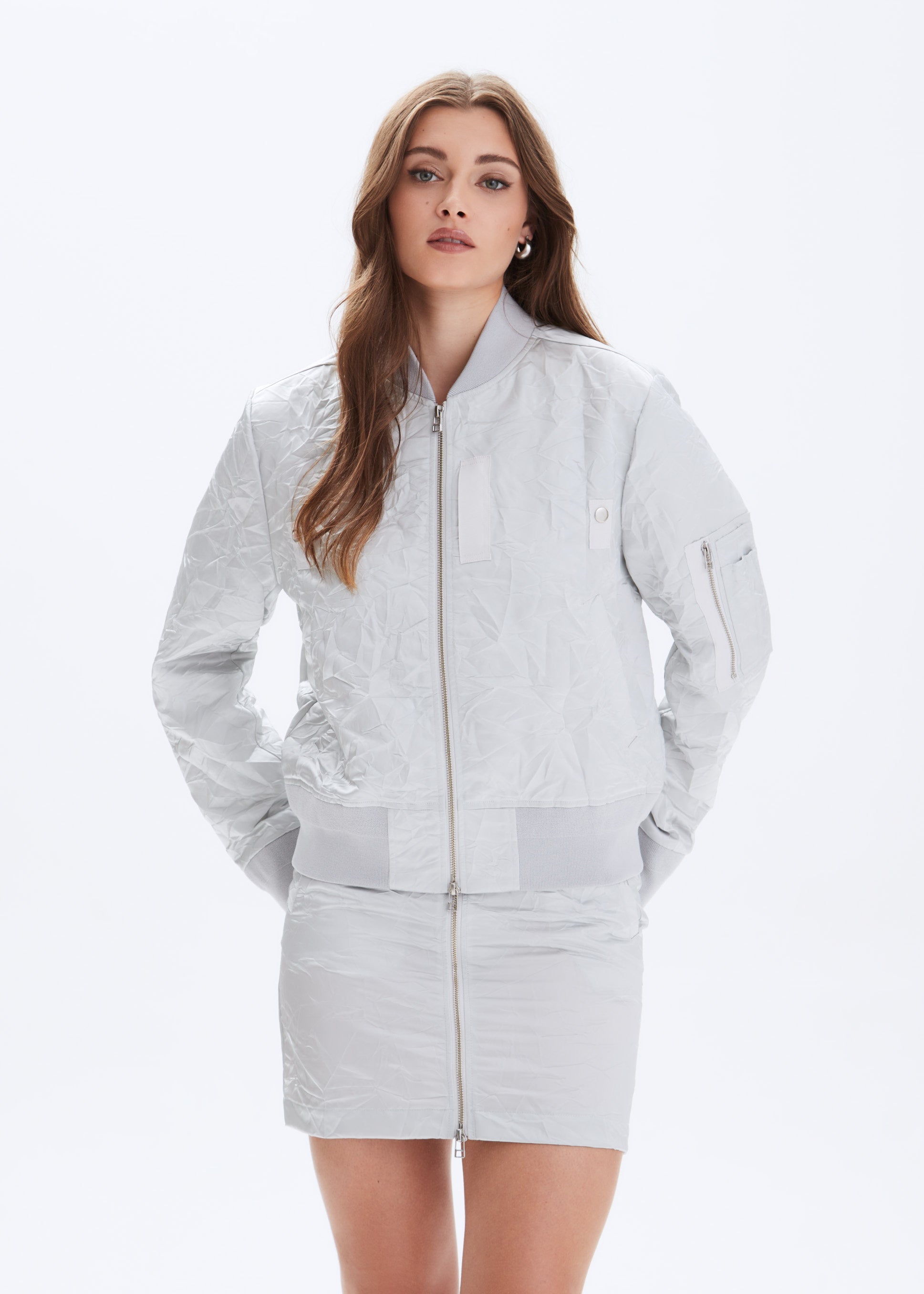 Woman wearing a light gray jacket and skirt set on a white background