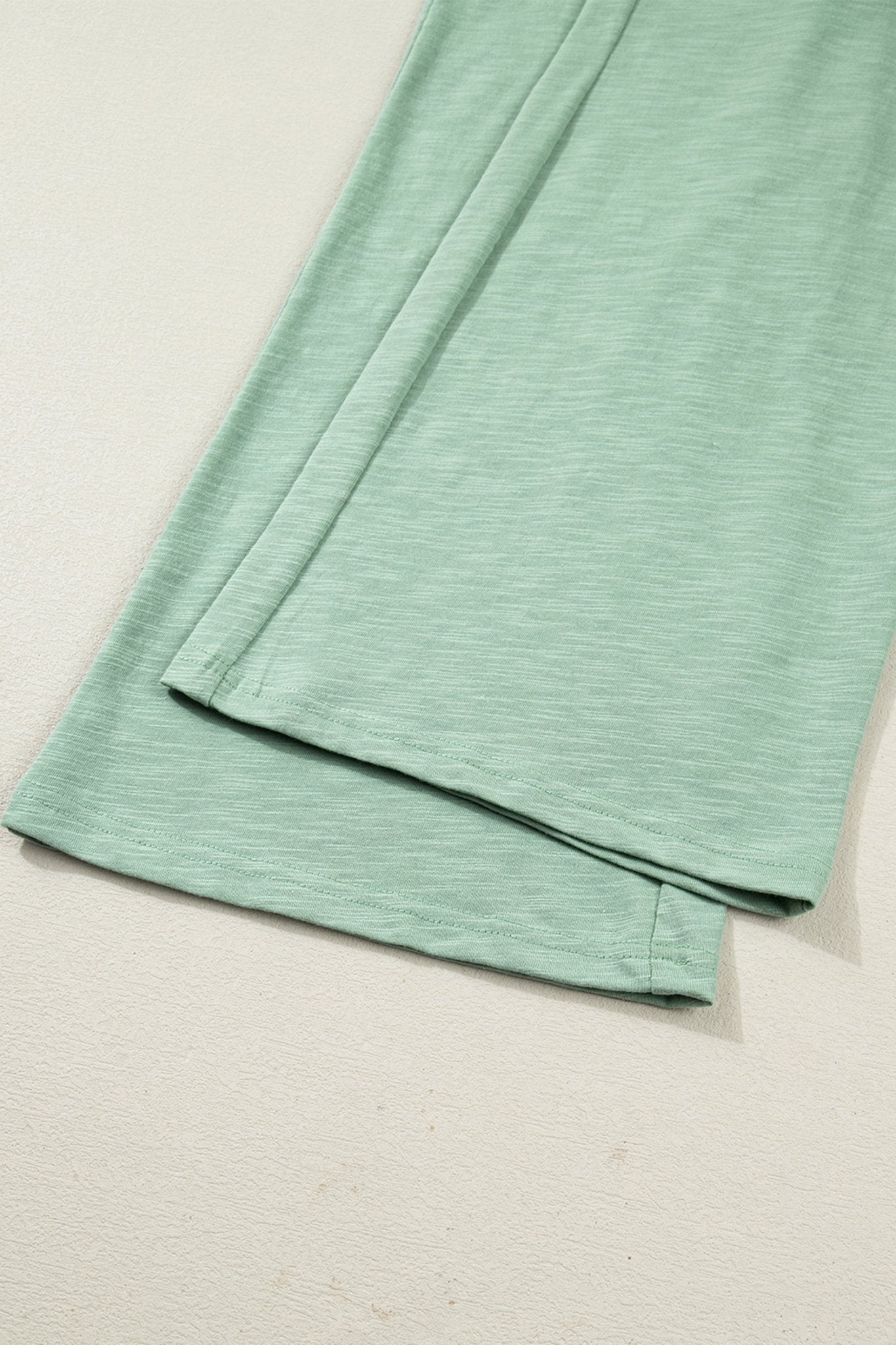 Folded green fabric on a beige surface