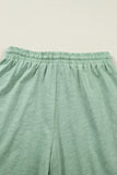 Close-up of green pants with an elastic waistband on a light beige background