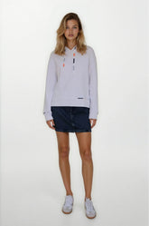 Woman wearing a light gray long-sleeve shirt with a collar and dark denim shorts on a white background