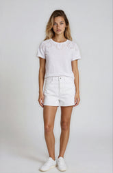 Woman wearing a white top and shorts with a plain background