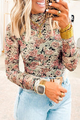 Woman wearing a floral long-sleeve top and jeans, holding a phone.