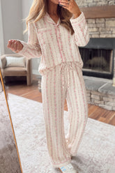 Woman in cream pajama set with pink floral vertical stripes.