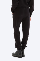 Person wearing black sweatpants and black shoes on a white background