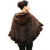 Woman wearing a brown knitted poncho with fur trim on a white background