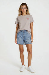Woman wearing a gray t-shirt with a logo and denim shorts on a white background