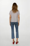 Woman wearing a light gray t-shirt and blue jeans on a white background