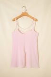 Pink tank top with lace trim on a wooden hanger against a beige background