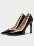 Black high-heeled shoes with studded details on a light gray background