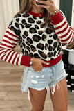 Woman in red-white-brown leopard cardigan with striped sleeves and distressed denim shorts.