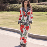 Woman wearing a floral outfit with red flowers and black patterns on a grassy background