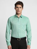 Man wearing a green checkered shirt and black pants on a white background