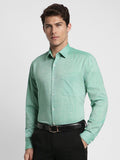 Man wearing a light green checkered shirt with black pants on a white background