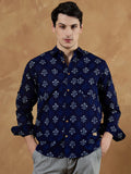 Man wearing a dark blue patterned shirt against a brown background