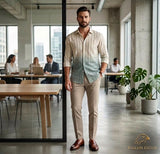 Man standing in a modern office with colleagues working in the background