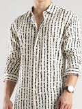 Man wearing a white shirt with black pattern on a plain background