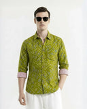Man wearing a green patterned shirt and sunglasses on a white background