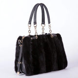 Black fur handbag with gold accents on a white background