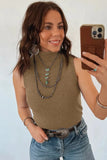 Woman taking a mirror selfie wearing a brown sleeveless top and blue jeans, with layered necklaces and bracelets.