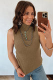 Woman taking a mirror selfie wearing a brown sleeveless top and blue jeans.