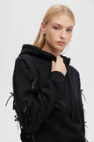 Person wearing a black hoodie with tassels on a white background