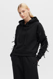 Person wearing a black hoodie with unique sleeve designs on a light gray background