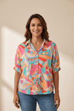 Woman wearing a colorful patterned shirt against a beige background